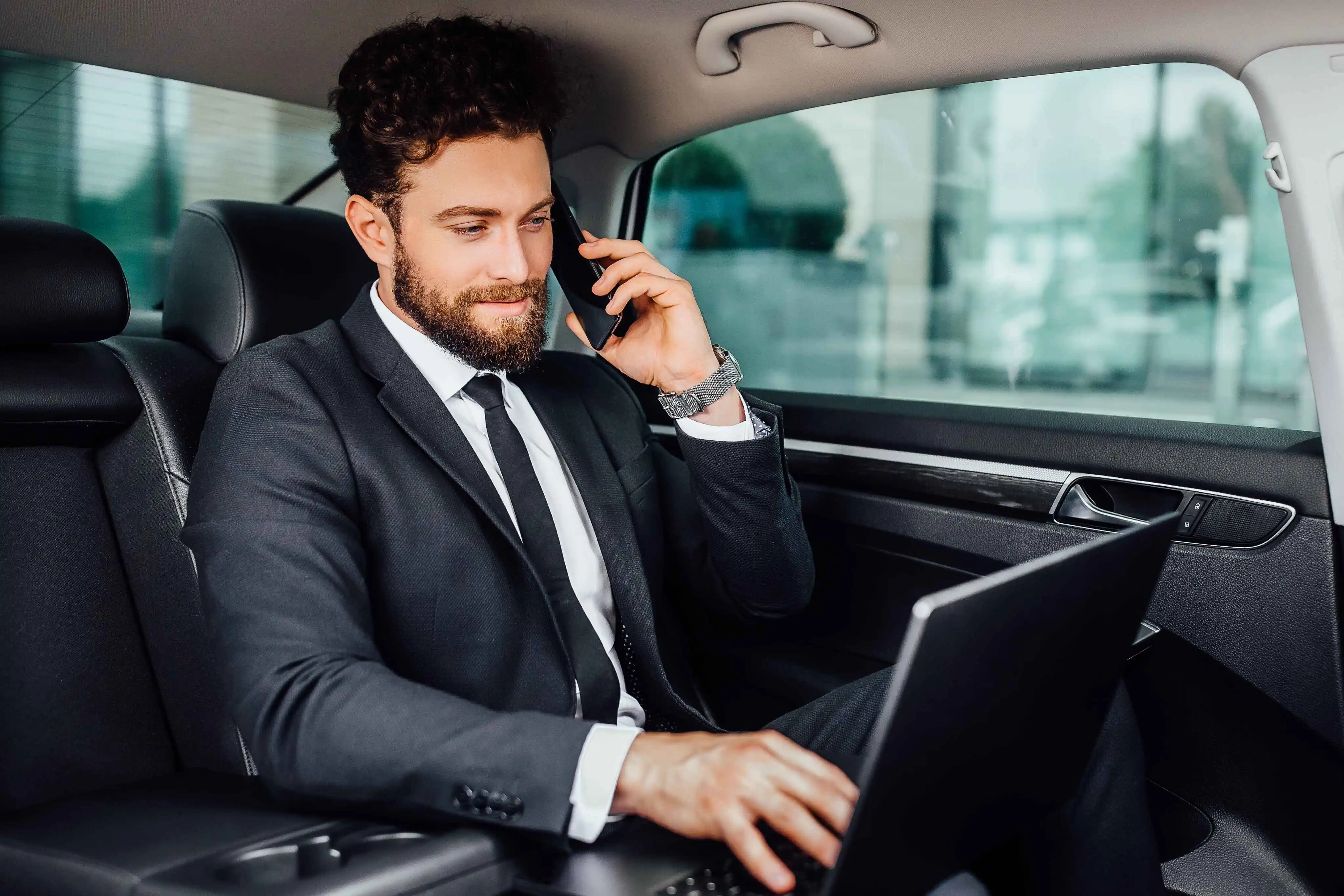 Passenger taking a call from the back seat of a Blackdoor Limo sedan